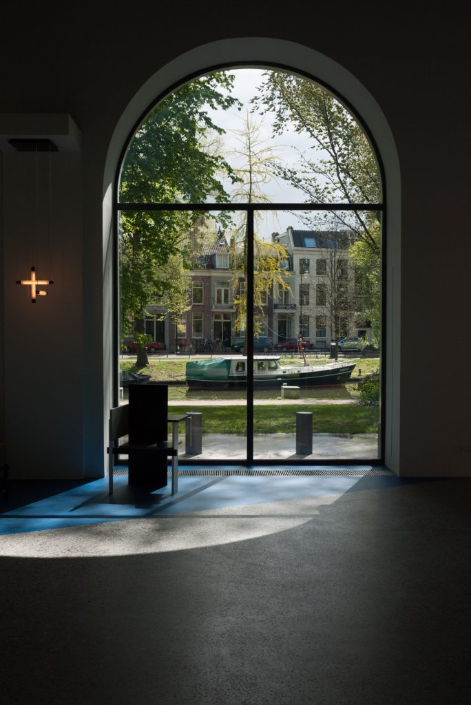 Looking through a window in the Centraal Museum in Utrecht onto Utrecht itself. A Boat is on the canal in front and further back is a street with tall Dutch houses.